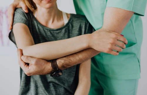Fysioterapeut undersöker en kvinnas arm och axel vid en bedömning på kliniken