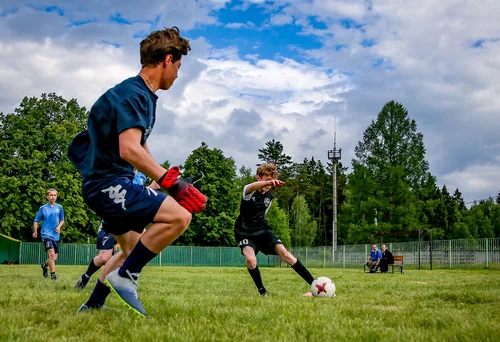 Unga fotbollsspelare i match, en spelare skjuter mot mål framför målvakten.